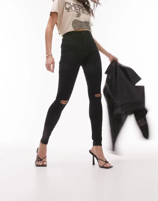 Topshop Joni jeans with knee rips in black sold by ASOS