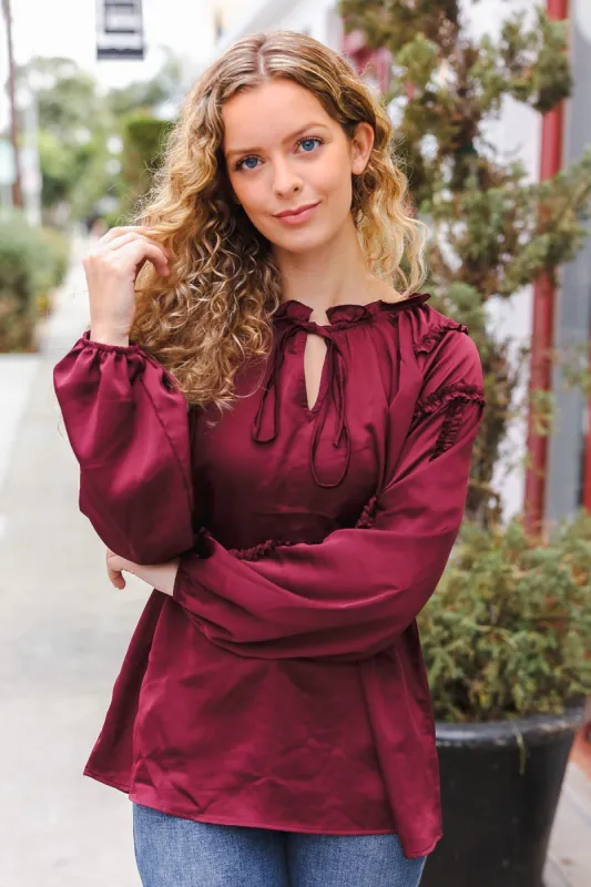 Holiday Vibes Burgundy Frill Detail Tie Neck Satin Top sold by Charming Charlie
