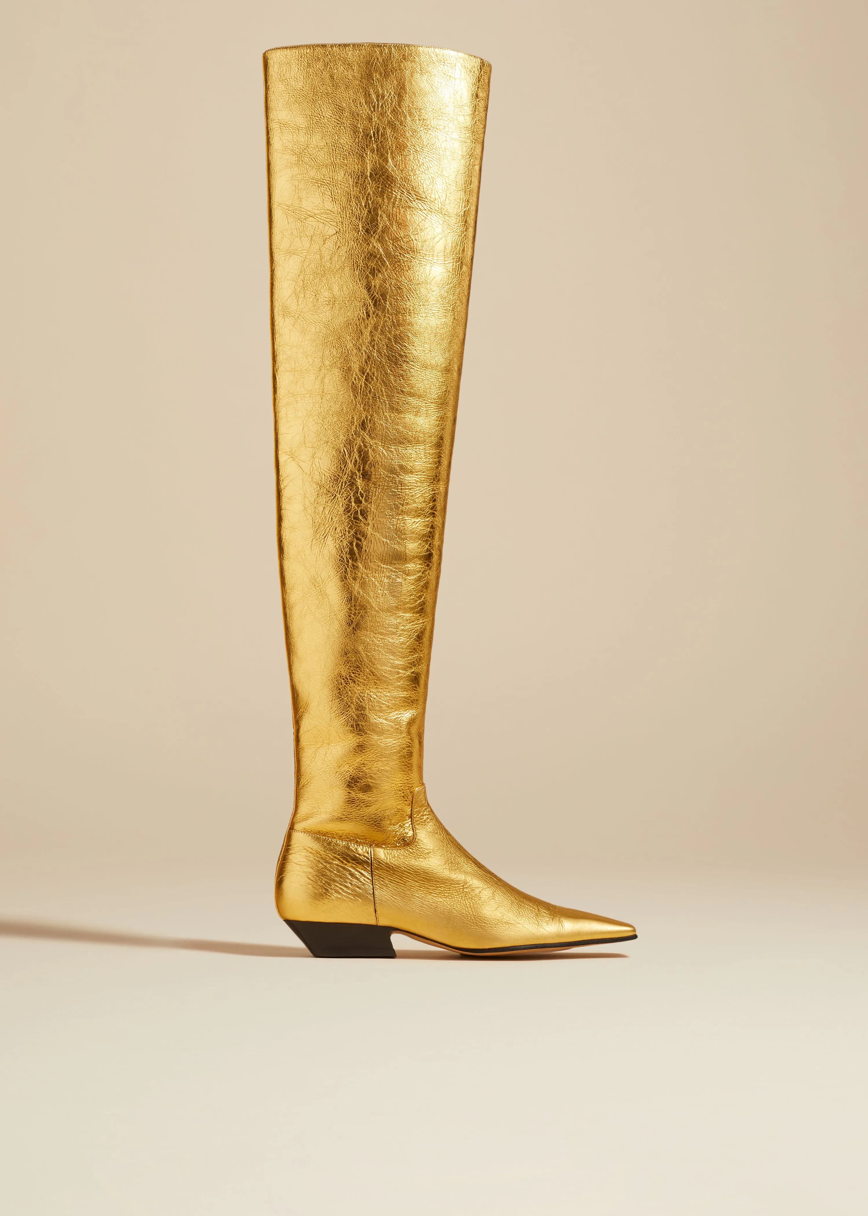 The Marfa Over-the-Knee Flat Boot in Gold Metallic Leather sold by KHAITE