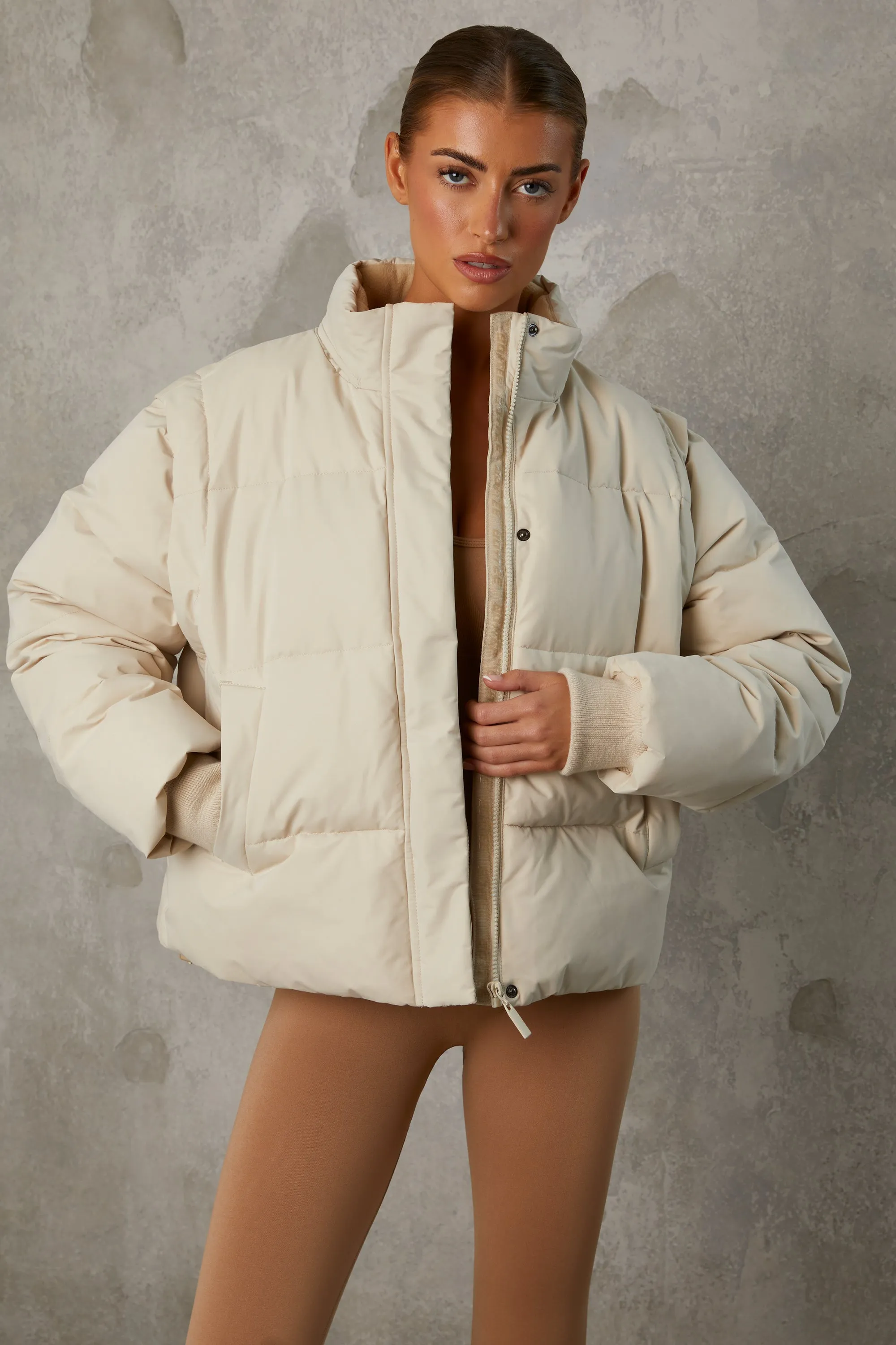 Cropped Puffer Jacket with Detachable Sleeves in Sand sold by Oh Polly