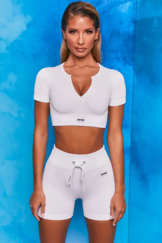 Perform Ribbed Short Sleeve Zip Front Crop Top in White sold by Oh Polly