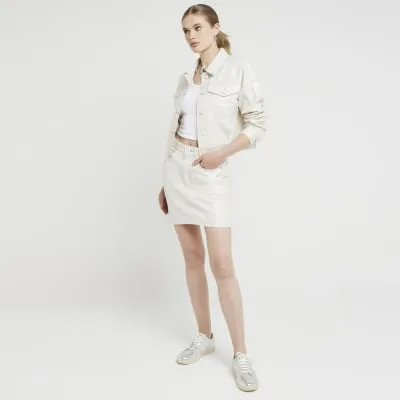 Beige metallic coated denim crop jacket sold by River Island