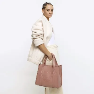 Pink embossed cross body tote bag sold by River Island