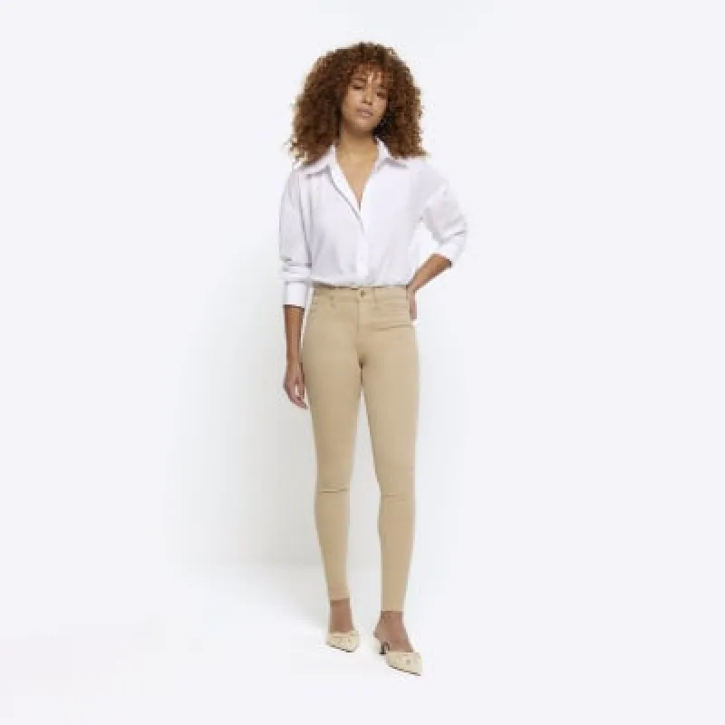 Cream mid rise bum sculpt jeggings sold by River Island
