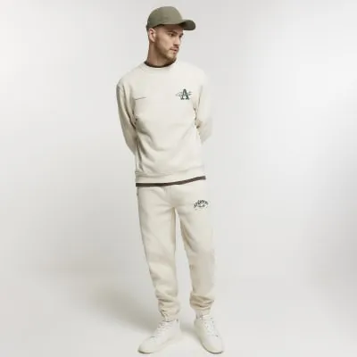 Beige regular fit graphic cuffed joggers sold by River Island