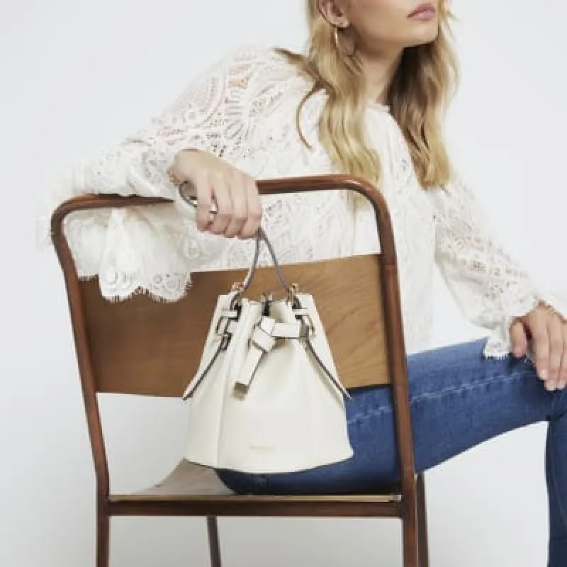 Cream cross body bucket bag sold by River Island