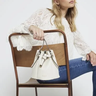 Cream cross body bucket bag sold by River Island
