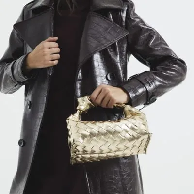 Gold Faux Leather Knot Woven Clutch Bag sold by River Island