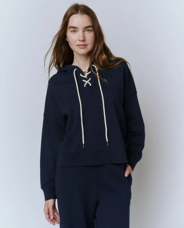 The Lace Up Hoodie. -- True Navy sold by THE GREAT.