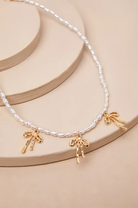 Desired Perfection Gold Pearl Rhinestone Bow Charm Necklace sold by Lulus