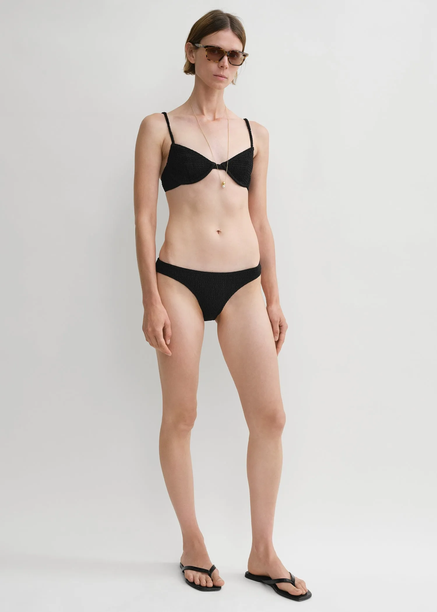 Smocked mid-rise bikini bottoms black sold by Toteme