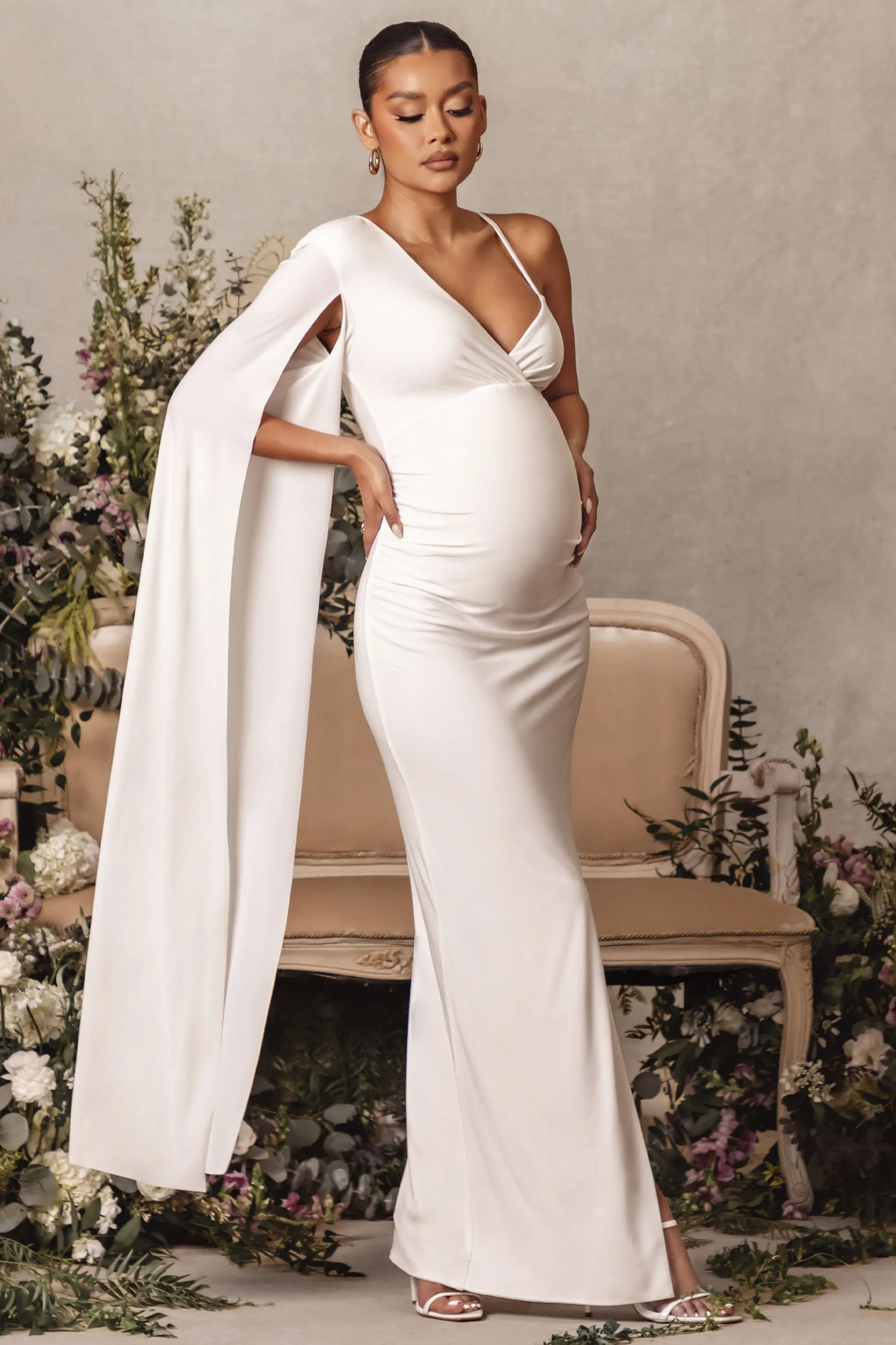 The Crown | White Asymmetric Plunge Maternity Maxi Dress with Cape Sleeve sold by Club L London