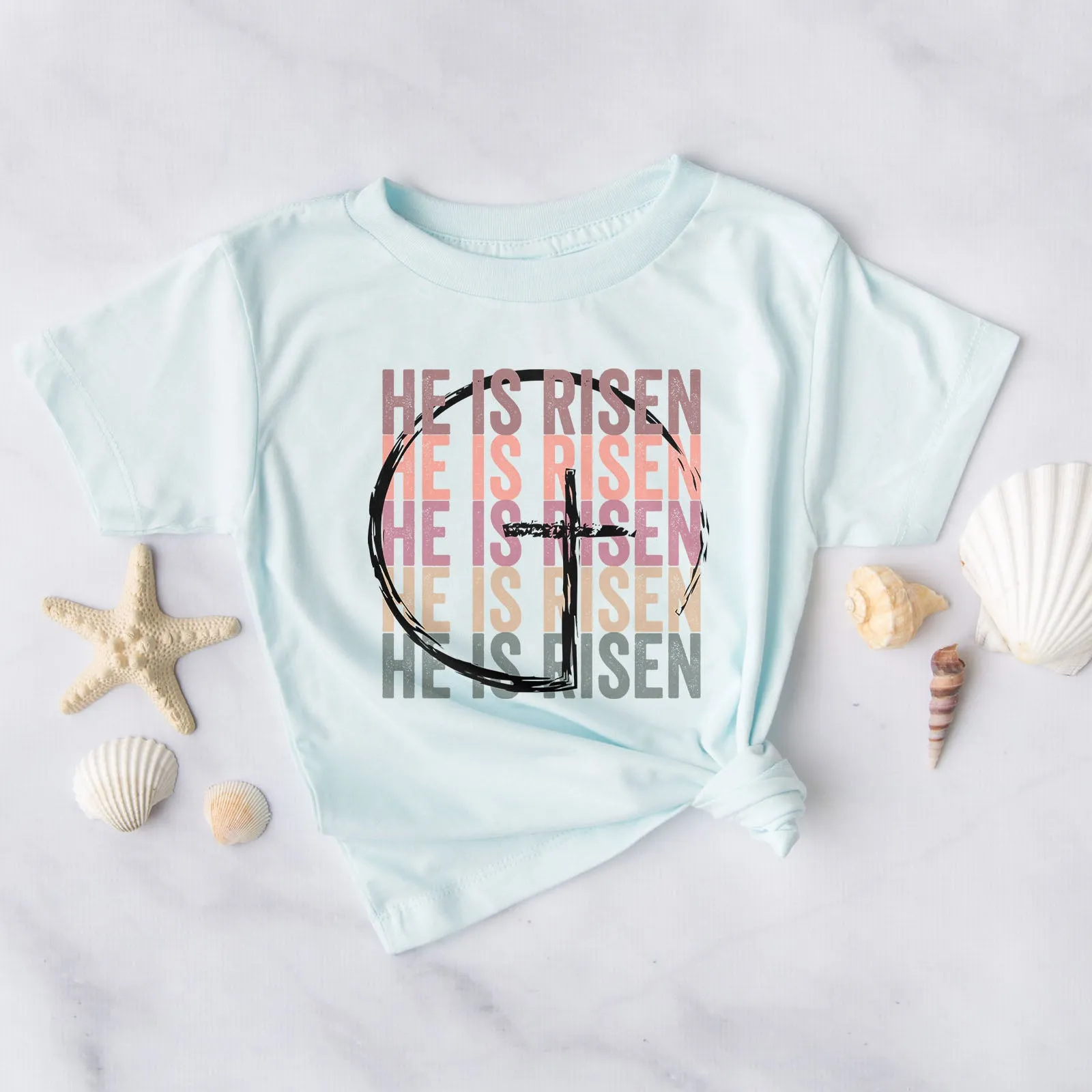 He Is Risen Stacked Easter Rainbow Tee sold by Faithful and Co.