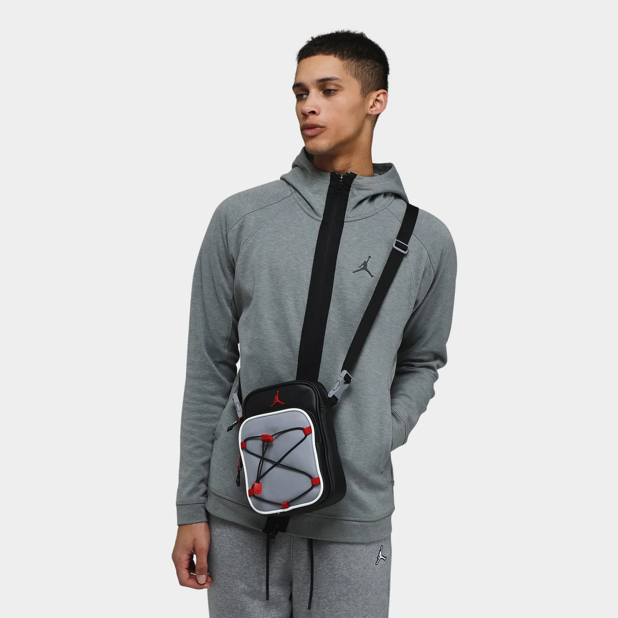 AJ FESTIVAL BAG /CEMENT GREY/GYM RED-BLACK` sold by JD Sports