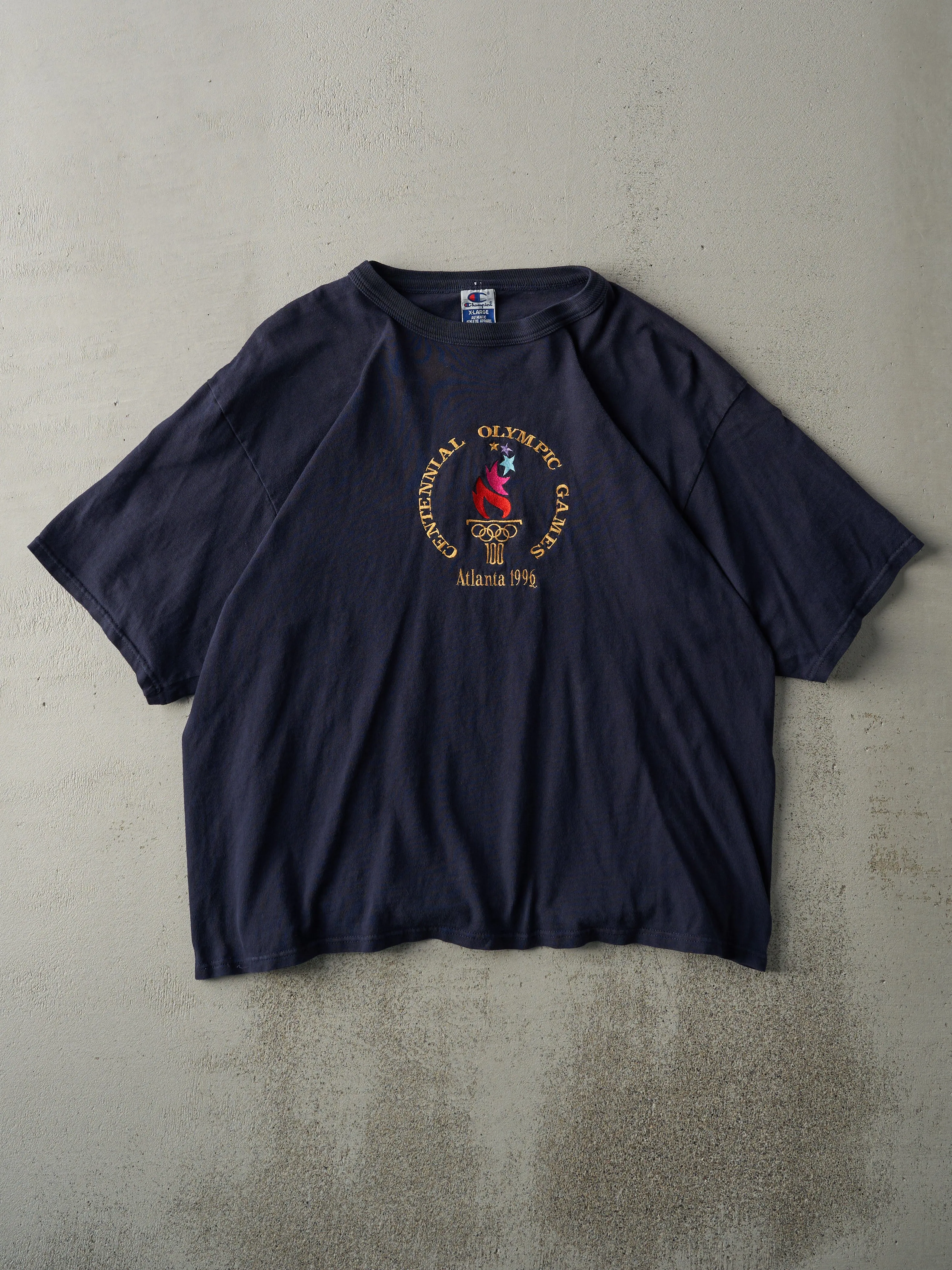Vintage 96' Navy Blue Embroidered Atlanta Olympics Champion Tee (L) sold by Rebalance Vintage