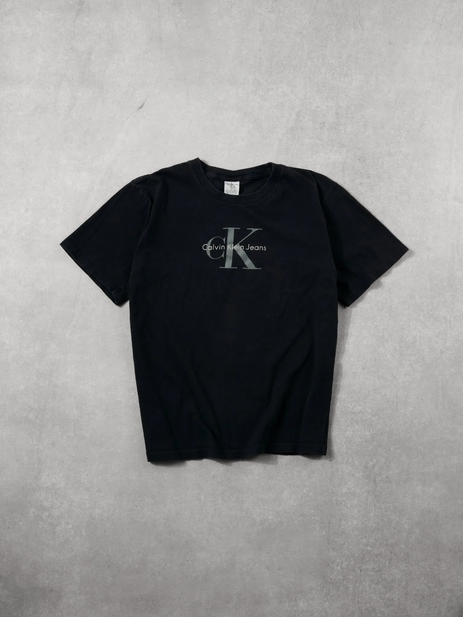 Vintage 90s Washed Black Clavin Klein Graphic Tee (M) sold by Rebalance Vintage