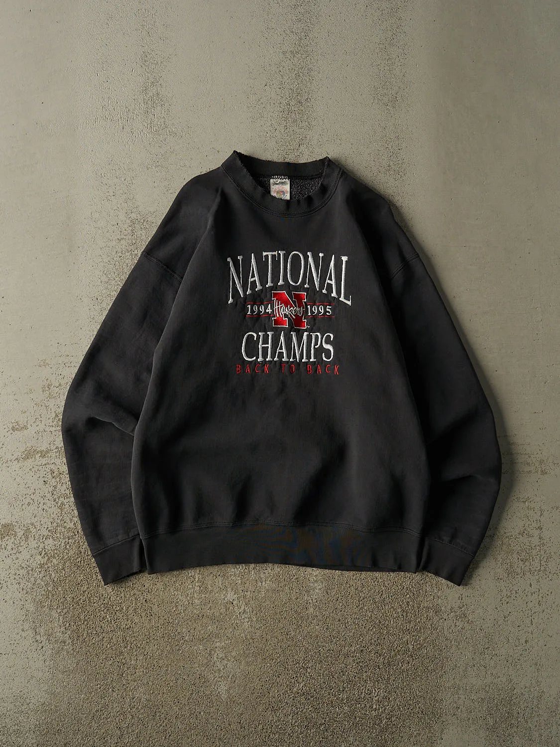 Vintage 95' Faded Black Nebraska University Embroidered Crewneck (L) sold by Rebalance Vintage