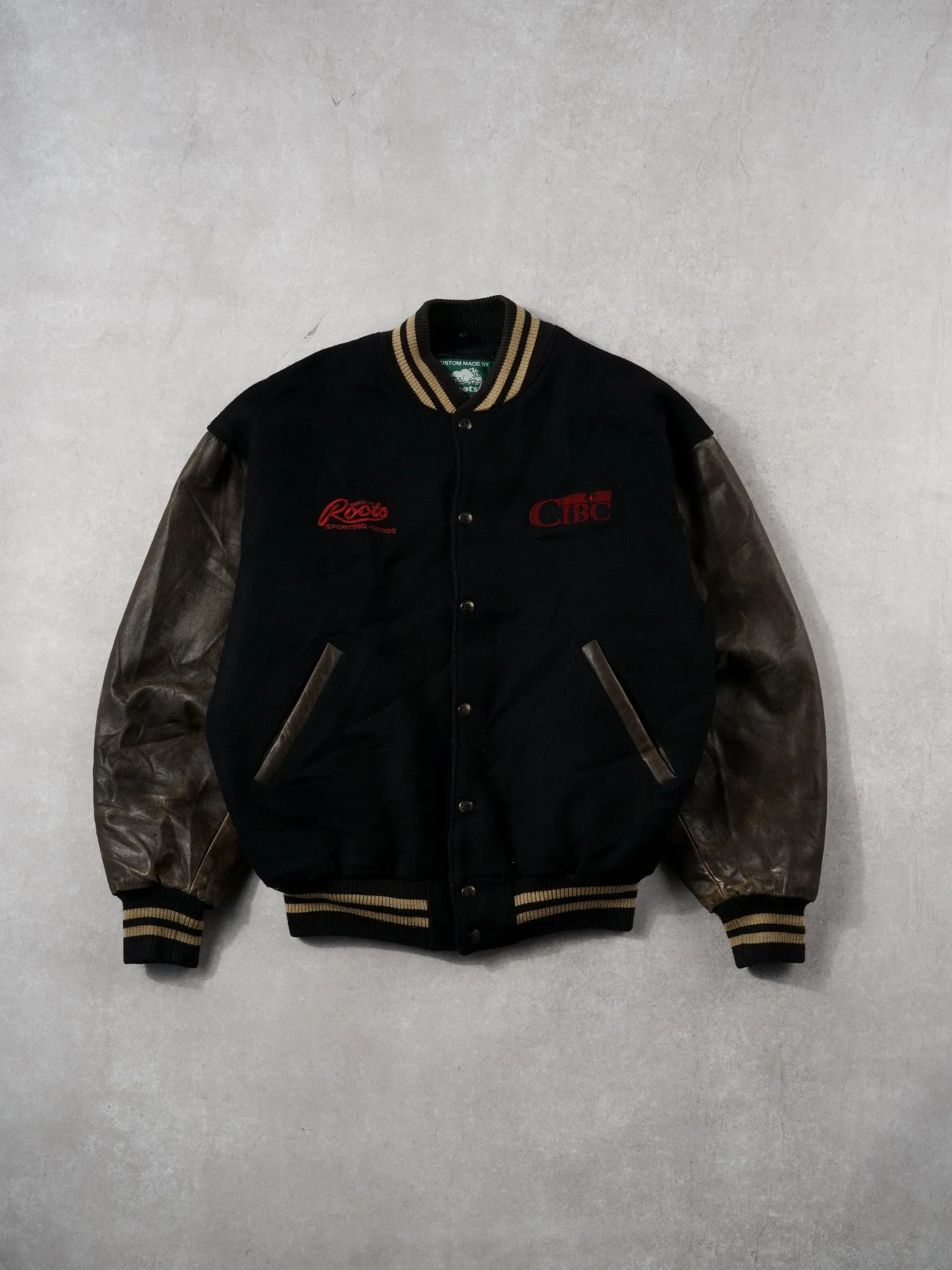 Vintage 90s Black and Brown Roots x CIBC Varsity Jacket (M) sold by Rebalance Vintage