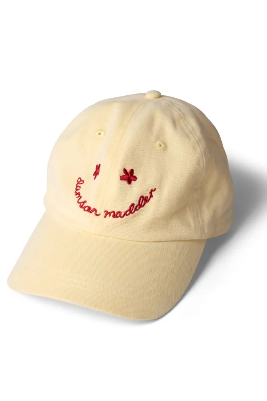 washed smiley cap in butter with red embroidery sold by Damson Madder