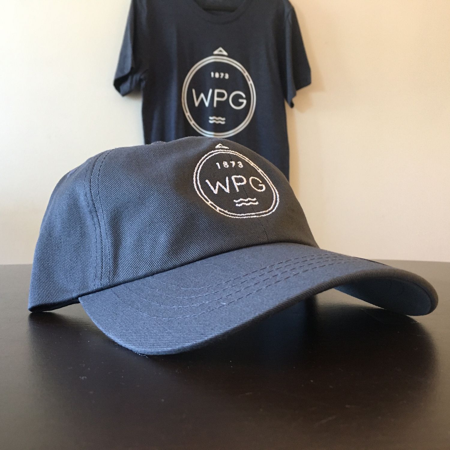 WPG Compass Dad Hat | White on Charcoal sold by We Heart Winnipeg